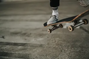 Skateboarder Expressing Style In Vans Checkered Shoes Wallpaper