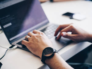 Sleek Silver Macbook Pro On A Wooden Desk Wallpaper