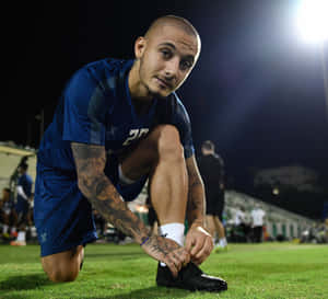 Soccer Player Tying Shoeon Field Wallpaper