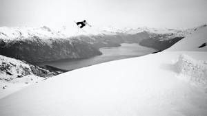 Spirited Snowboarder Surfing The Snowy Peaks Wallpaper