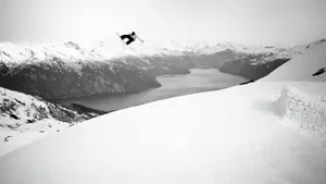 Spirited Snowboarder Surfing The Snowy Peaks Wallpaper