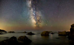 Star Sky Over Rocky Body Of Water Wallpaper