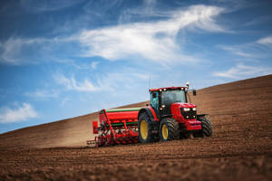 Sturdy Red Tractor On A Farm Field Wallpaper