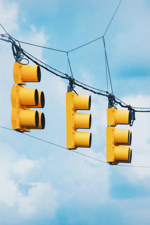 Suspended Yellow Traffic Lights Against A Clear Sky Wallpaper