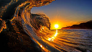 Take A Moment To Appreciate The Beauty Of A Stunning Sunset Over The Waves. Wallpaper