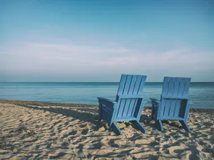 Take In The Ocean Views From The Comfort Of A Blue Beach Chair Wallpaper