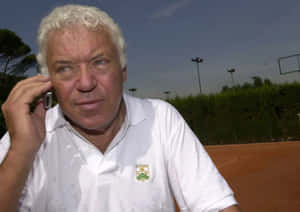 Tennis Veteran On Phone Courtside Wallpaper