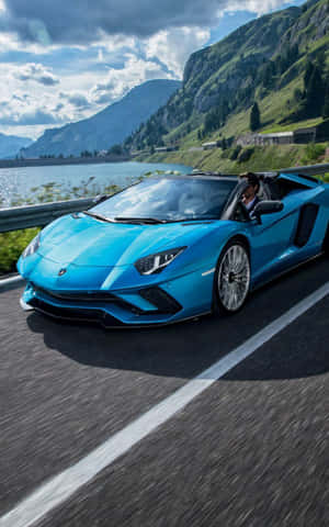 The Blue Lamborghini Spyder Is Driving Down The Road Wallpaper