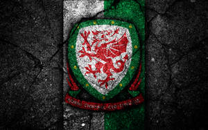 The Strength Of Wales - National Football Team's Logo Etched Onto Cracked Pavement Wallpaper