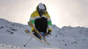 Thrilling Moment Of A Ski Jumper In Mid-flight At A Competitive Ski Jumping Event Wallpaper