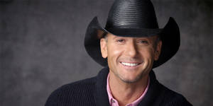 Tim Mcgraw Smiling Against Limewash Wall Wallpaper