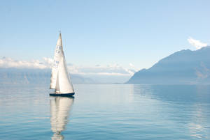 Tranquil Moment Of A Yacht Sailing In The Emerald Sea Wallpaper