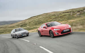 Two Cars Are Driving Down A Road Wallpaper