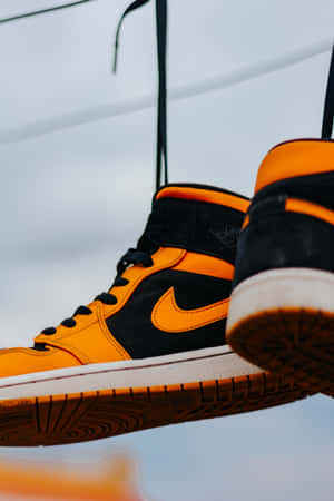 Two Pairs Of Air Jordan 1 Mid Sneakers Hanging On A Clothesline Wallpaper