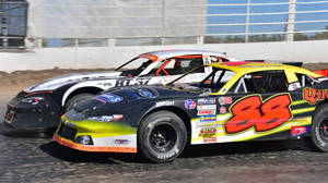 Two Race Cars Racing On A Dirt Track Wallpaper