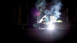 Two Welders Working On A Metal Piece Wallpaper