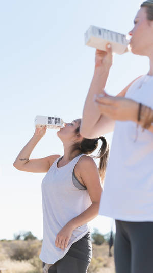 Two Women Drinking Water From Box Wallpaper