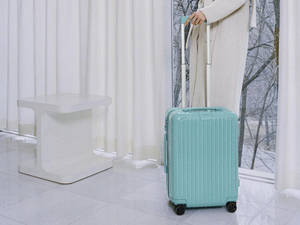 Woman Holding A Glacier Blue Rimowa Wallpaper