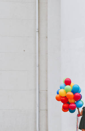 Woman Holding Bunch Of Colorful Balloons Wallpaper