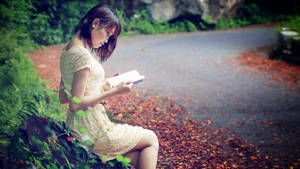 Woman Reading Beside Road Wallpaper