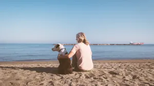 Woman Sitting On Beach With Dog Wallpaper