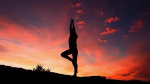 Yoga Stance Under Sunset Sky Wallpaper