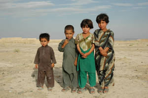 Young Boys In Traditional Attire Observing The Rural Landscapes Of Afghanistan Wallpaper