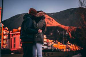 Young Love - Couple Embracing In A Sunlit Field Wallpaper