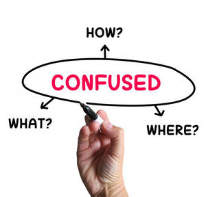 Young Man Standing At A Crossroads, Looking Lost And Confused. Wallpaper